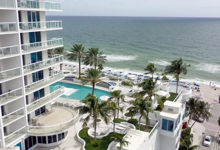 Hilton Fort Lauderdale Beach Resort view. Palm trees, pool, and ocean. Gay-friendly hotel for gay men travel advice in Florida.