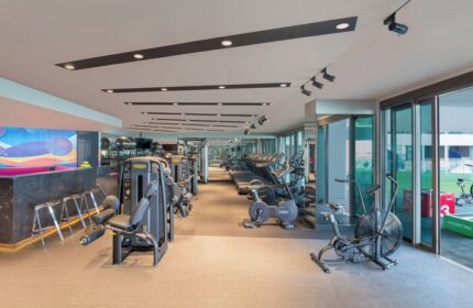 Gym at W Dubai - The Palm, a gay-friendly hotel. Fitness center with treadmills, bikes, and weight machines. Modern design, well-lit space.