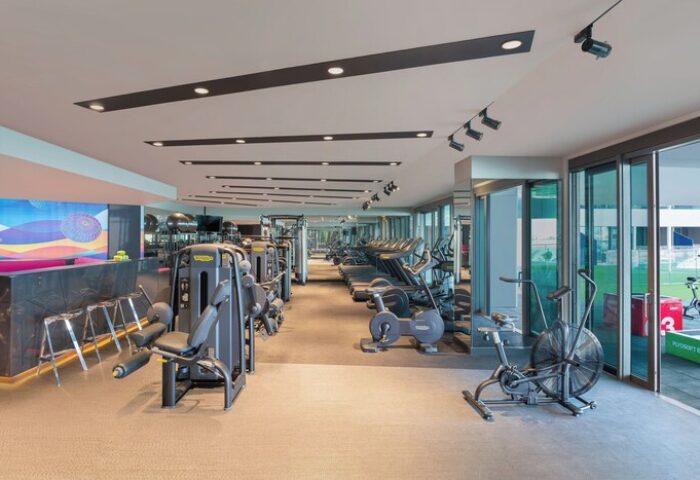 Gym at W Dubai - The Palm, a gay-friendly hotel. Fitness center with treadmills, bikes, and weight machines. Modern design, well-lit space.