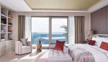 Raffles Istanbul Hotel room. Gay-friendly hotel with a view. Luxury bedroom with a chaise lounge, chair, and a beautiful city view.