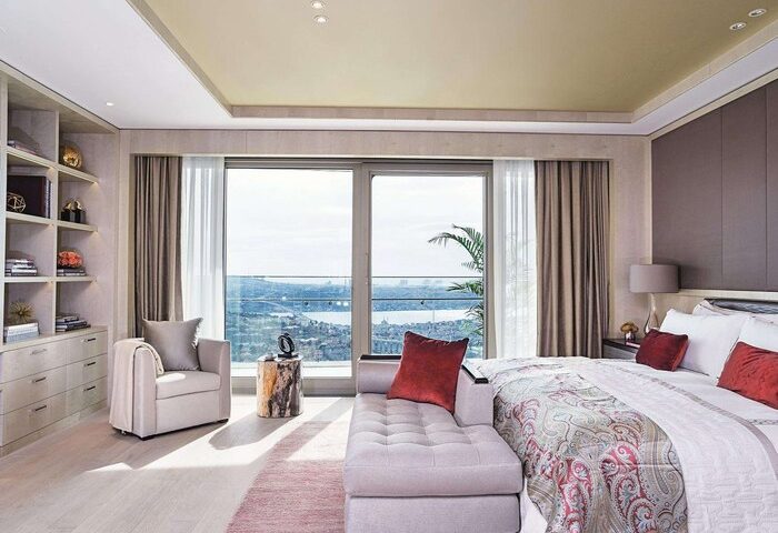 Raffles Istanbul Hotel room. Gay-friendly hotel with a view. Luxury bedroom with a chaise lounge, chair, and a beautiful city view.