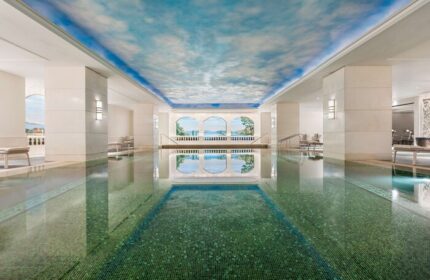 Indoor pool at Shangri-La Bosphorus, Istanbul, a gay-friendly hotel. The pool has a blue sky ceiling and mural, creating a serene atmosphere.