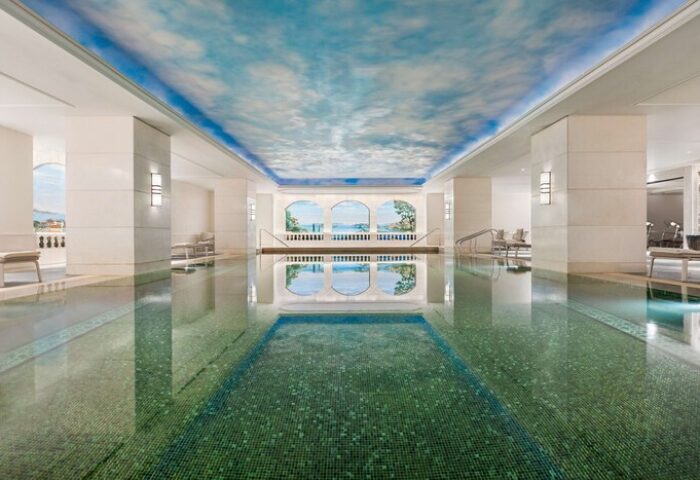 Indoor pool at Shangri-La Bosphorus, Istanbul, a gay-friendly hotel. The pool has a blue sky ceiling and mural, creating a serene atmosphere.