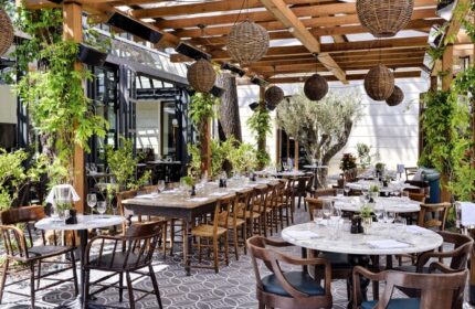 Soho House Istanbul's gay-friendly hotel outdoor dining area. Tables, chairs, plants, and decorative lighting create an inviting atmosphere.