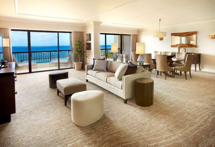 Hilton Hawaiian Village suite interior. Waikiki Beach Resort gay-friendly hotel room with ocean view, living area, dining table, and neutral decor.