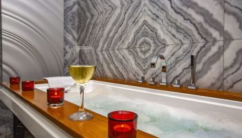 Elysium Taksim Hotel gay-friendly bath. Wine glass and candles by a tub with marble tile. Relax at this gay Istanbul hotel.