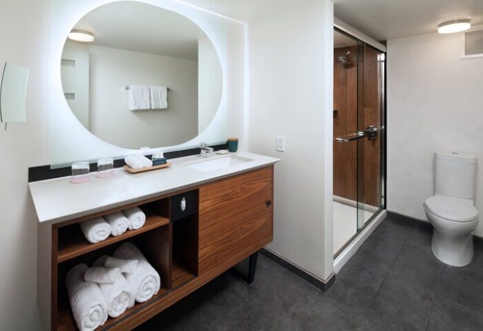 The Laylow Autograph Collection gay-friendly hotel bathroom. Modern design with round mirror, vanity, shower, and toilet. Great for gay men travel.