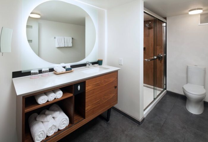 The Laylow Autograph Collection gay-friendly hotel bathroom. Modern design with round mirror, vanity, shower, and toilet. Great for gay men travel.