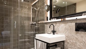 Bathroom at SCHLOSS Roxburghe Hotel, a gay-friendly hotel. Shower with glass door, sink, and mirror. Modern design, ideal for gay travel.