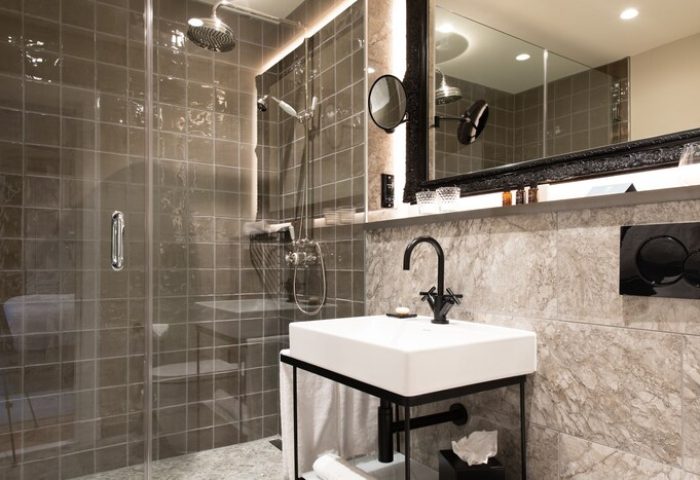 Bathroom at SCHLOSS Roxburghe Hotel, a gay-friendly hotel. Shower with glass door, sink, and mirror. Modern design, ideal for gay travel.