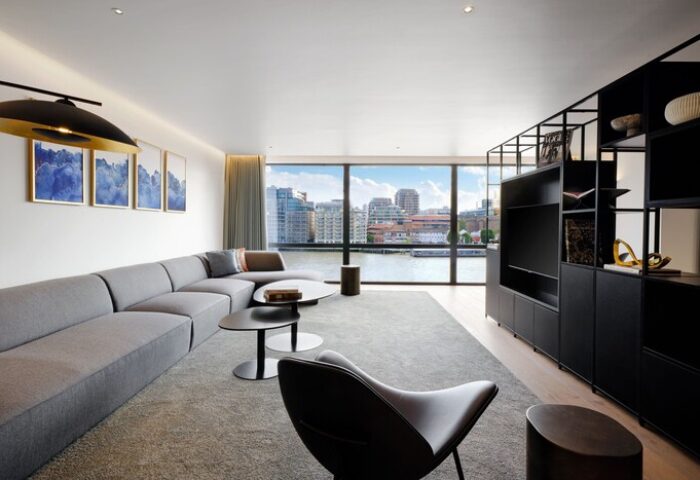 The Westin London City gay-friendly hotel room. Modern interior with river view, gray sofa, black chair, and sleek design. Luxury gay travel.