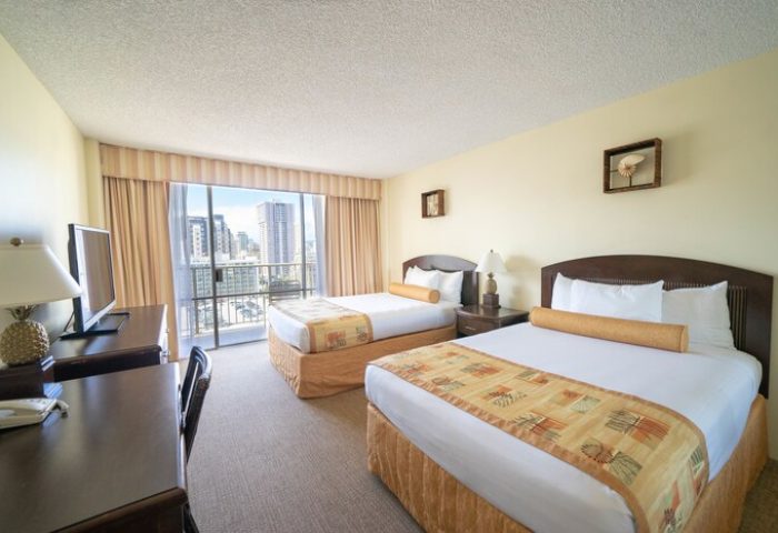 OHANA Waikiki East by OUTRIGGER room with two beds, desk, TV, and balcony view of Honolulu. Gay-friendly hotel for gay men travelers.