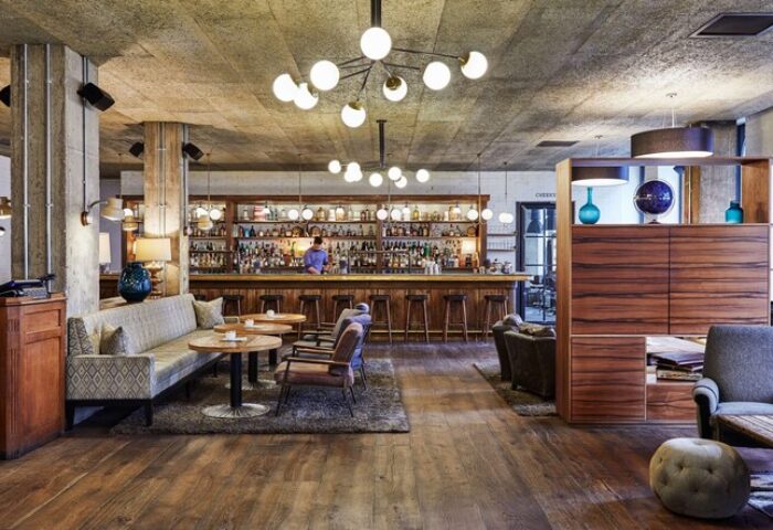The Hoxton, Holborn: Interior of a gay-friendly hotel bar. Stylish lounge area with seating, bar, and lighting. Wooden floors and modern design.