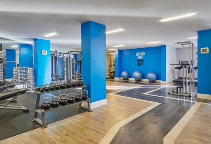 Fairmont St Andrews gym, Scotland. Gay-friendly hotel with fitness center, weights, treadmills, and exercise equipment. Blue accent wall, modern design.
