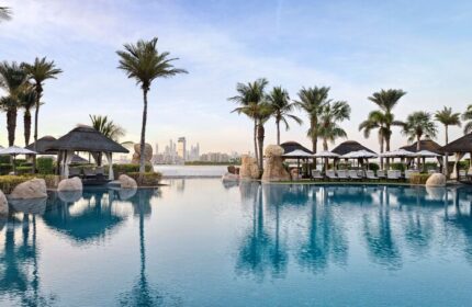 Sofitel Dubai The Palm Resort pool view. Gay-friendly hotel with palm trees, cabanas, and Dubai skyline. Perfect for gay travel and relaxation.