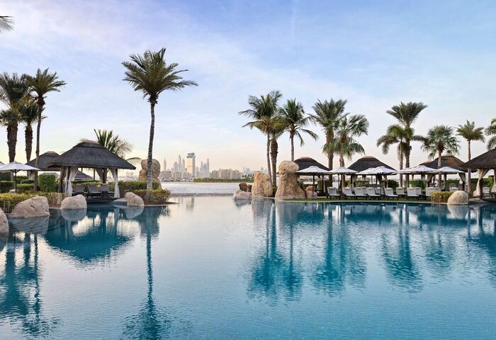 Sofitel Dubai The Palm Resort pool view. Gay-friendly hotel with palm trees, cabanas, and Dubai skyline. Perfect for gay travel and relaxation.