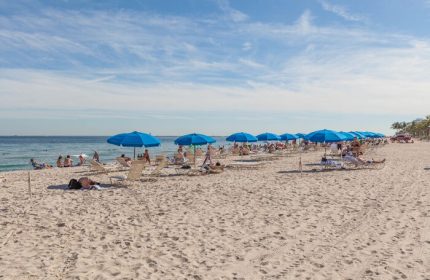 Sonesta Fort Lauderdale Beach: People relaxing under blue umbrellas on the beach. Gay-friendly hotel with ocean views.