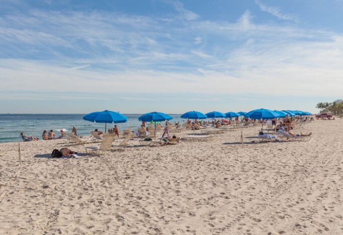 Sonesta Fort Lauderdale Beach: People relaxing under blue umbrellas on the beach. Gay-friendly hotel with ocean views.