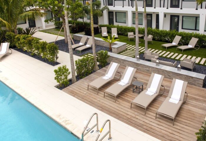 Elita Hotel's gay-friendly pool area. Lounge chairs on a wooden deck next to the pool. Tropical landscaping. A relaxing space for gay travelers.
