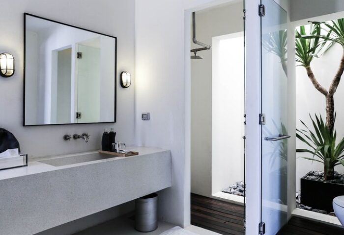 Cross River Kwai gay-friendly hotel bathroom. Modern design with stone sink, mirror, shower, and indoor plant. X2 River Kwai luxury travel.