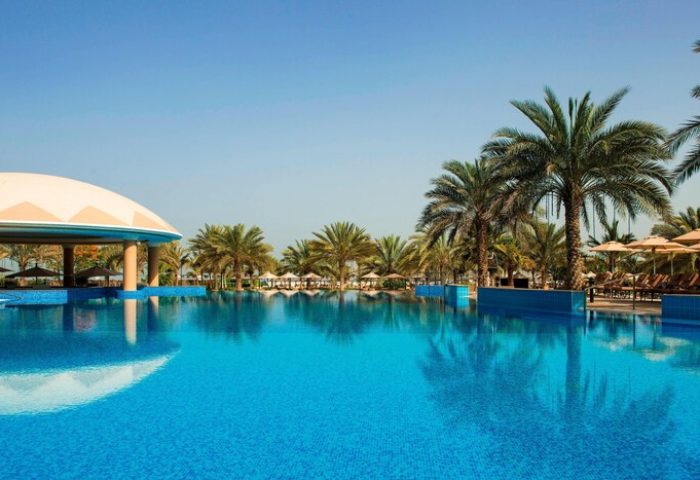 Le Royal Méridien Beach Resort & Spa pool view. Gay-friendly hotel with palm trees, blue water, and a clear sky. Perfect for gay travel.
