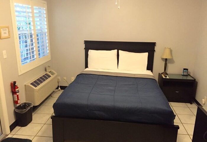 Coral Reef Guesthouse room. Gay-friendly hotel with bed, nightstand, lamp, and window. A comfortable stay for gay travelers.