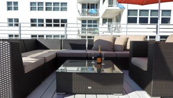 Gay-friendly hotel rooftop lounge. Wicker furniture, champagne, and glasses on a glass table. Perfect for relaxing at this gay hotel.