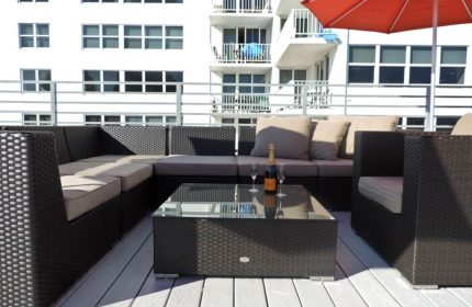 Gay-friendly hotel rooftop lounge. Wicker furniture, champagne, and glasses on a glass table. Perfect for relaxing at this gay hotel.
