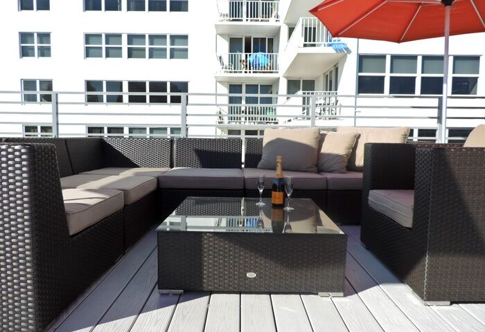Gay-friendly hotel rooftop lounge. Wicker furniture, champagne, and glasses on a glass table. Perfect for relaxing at this gay hotel.