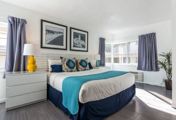 Nobleton Hotel's gay-friendly room. Queen bed with blue accents, white dresser, and beach-themed art. Inviting space for gay travelers.
