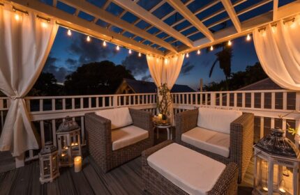 Alexander's Guesthouse gay-friendly hotel patio. Outdoor seating area with wicker furniture, string lights, and lanterns at dusk. Relaxing gay travel.
