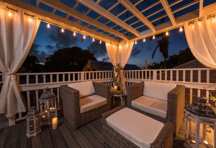 Alexander's Guesthouse gay-friendly hotel patio. Outdoor seating area with wicker furniture, string lights, and lanterns at dusk. Relaxing gay travel.