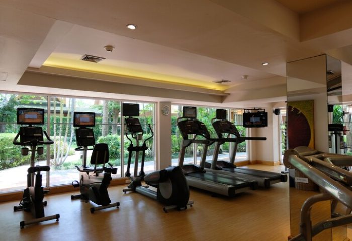 The Barai Hyatt gym, a gay-friendly hotel. Treadmills, bikes, and ellipticals face windows with green views. Fitness center.