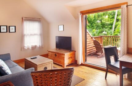 Island City House gay-friendly hotel room. Living area with balcony, chair, TV, and couch. Perfect for gay travelers seeking comfort and style.
