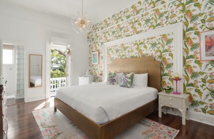 Marrero's Guest Mansion gay-friendly hotel room. Bedroom with tropical wallpaper, bed, balcony, and chandelier. Gay travel lodging in Key West.