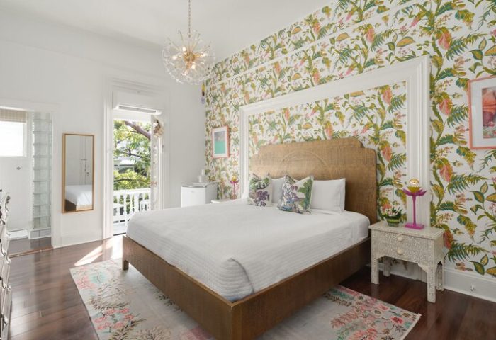 Marrero's Guest Mansion gay-friendly hotel room. Bedroom with tropical wallpaper, bed, balcony, and chandelier. Gay travel lodging in Key West.