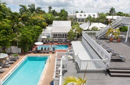 NYAH Key West adult-only gay-friendly hotel. Multiple pools, lounge chairs, & rooftop deck. Tropical foliage surrounds the resort.