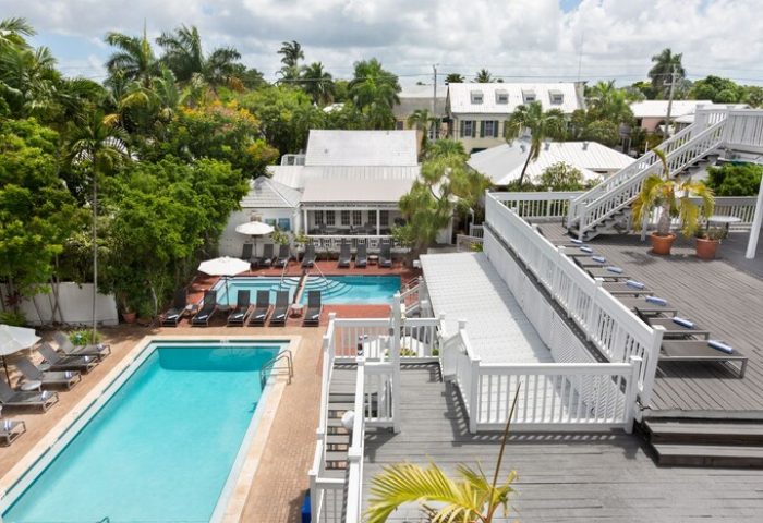 NYAH Key West adult-only gay-friendly hotel. Multiple pools, lounge chairs, & rooftop deck. Tropical foliage surrounds the resort.