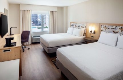 Hampton Inn & Suites Miami/Brickell-Downtown gay-friendly hotel room. Two beds with white linens, desk, TV, and city view. Modern, comfortable stay.