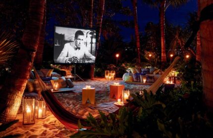 Outdoor movie night at The Miami Beach EDITION, a gay-friendly hotel. Hammock, candles, and classic film create a romantic, tropical vibe.