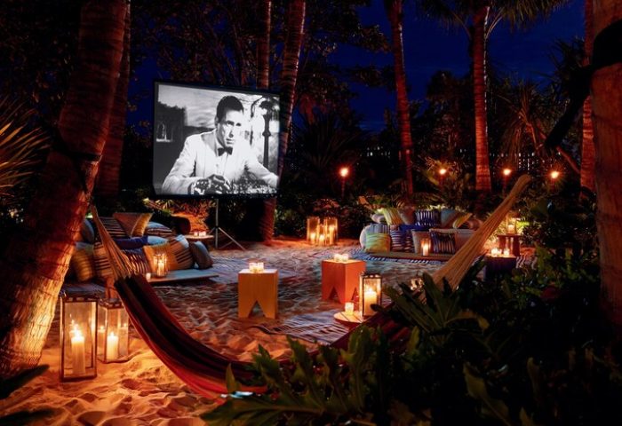 Outdoor movie night at The Miami Beach EDITION, a gay-friendly hotel. Hammock, candles, and classic film create a romantic, tropical vibe.