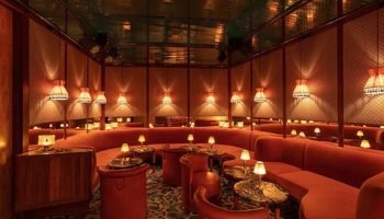 Interior of The Standard Miami, a gay-friendly hotel. Red seating wraps around tables with lamps. A stylish, welcoming space.