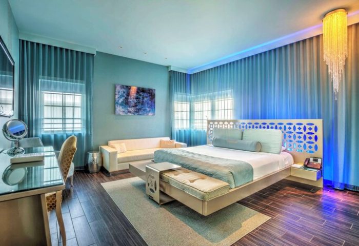 Dream South Beach, a gay-friendly hotel room. Modern design with blue accents, a king-size bed, and a seating area. Upscale and stylish.
