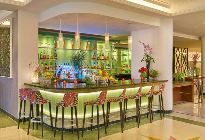 Bar at Royal Palm South Beach Miami, a gay-friendly Tribute Portfolio Resort. The bar has floral stools and a green illuminated back.