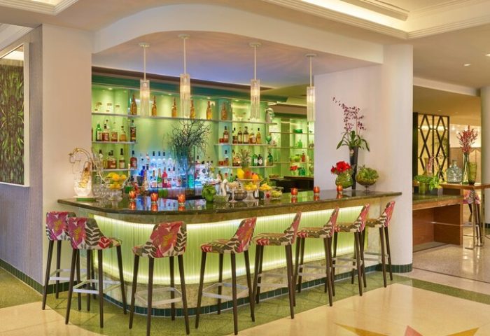 Bar at Royal Palm South Beach Miami, a gay-friendly Tribute Portfolio Resort. The bar has floral stools and a green illuminated back.