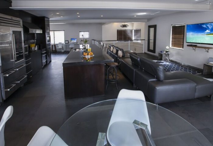 Posh South Beach gay-friendly hotel interior. Modern design with kitchen, island, living area, and TV. Upscale accommodation for gay travelers.