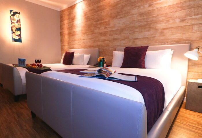 Hotel Shelley gay-friendly hotel room with two beds. Modern decor, wood-look wall, purple accents. Comfortable stay for gay travelers.