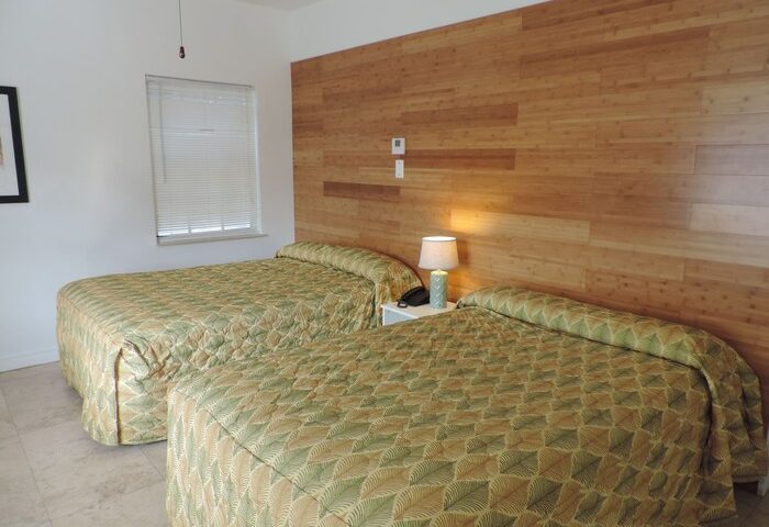 James Hotel room with two beds and wood paneling. Gay-friendly hotel accommodation featuring a clean, comfortable space for travelers.