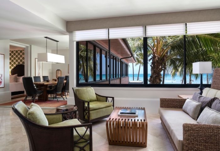 Royal Hawaiian luxury suite living area, Waikiki. Gay-friendly hotel with ocean view, dining table, sofa, and chairs. Perfect for gay travel.