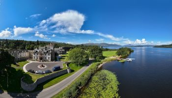 Cameron House on Loch Lomond: Gay-friendly hotel aerial view. Lochside resort with seaplane on the water. Scenic Scottish Highlands travel.